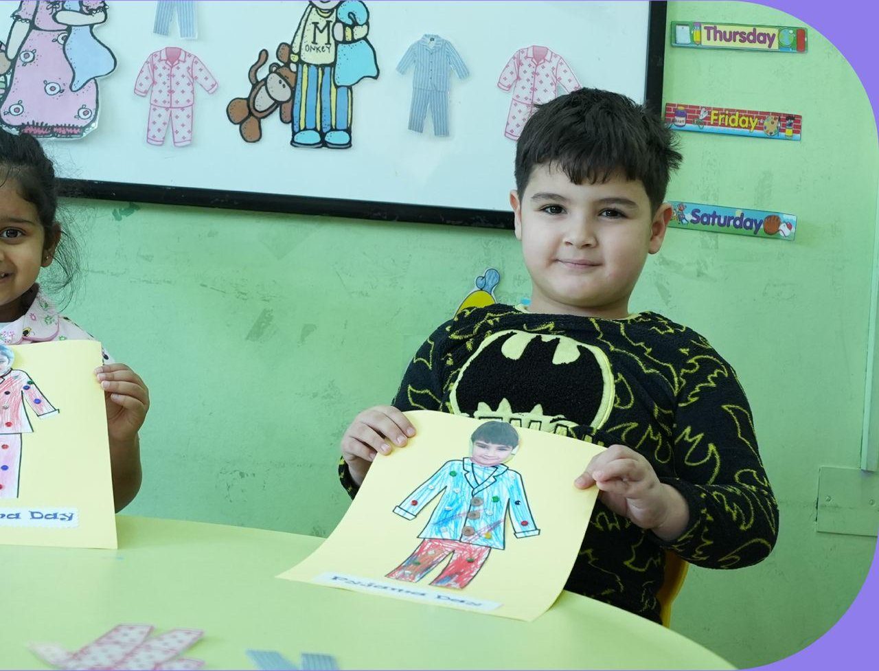 A boy proudly showing the self-portrait craft he made in class
